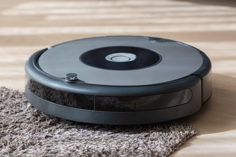 Robot vacuum on the edge of a rug on a wood floor
