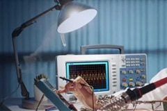 Woman using soldering iron and oscilloscope
