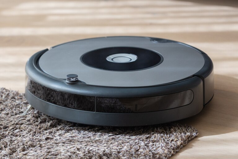 Robot vacuum on the edge of a rug on a wood floor